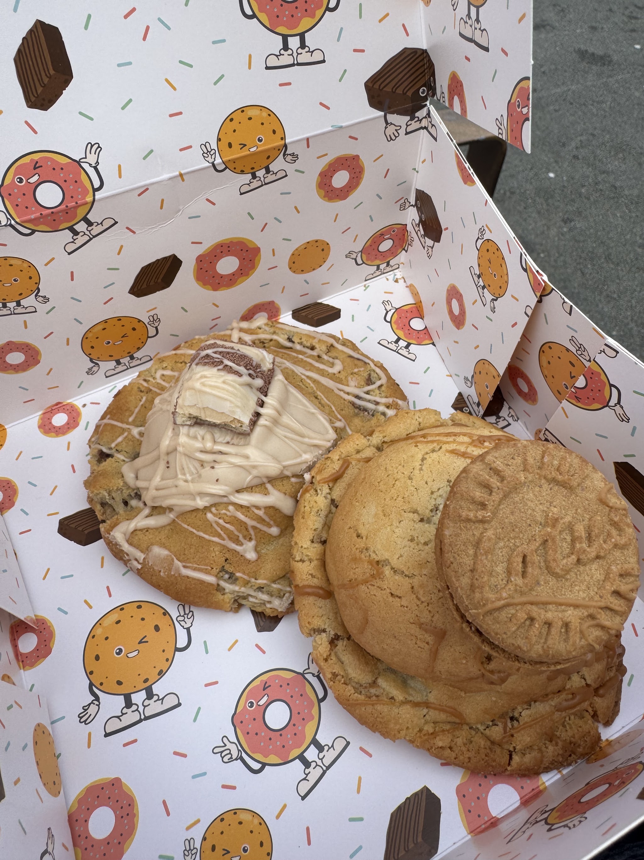 Two generously topped cookies in an illustrated bakery box